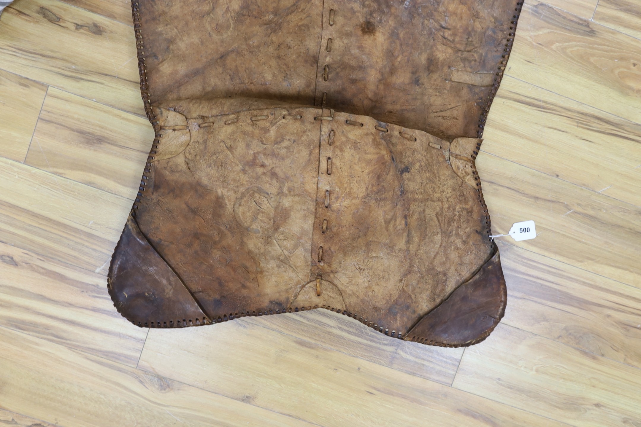 A shaped embossed leather chair seat, with leather thong edging